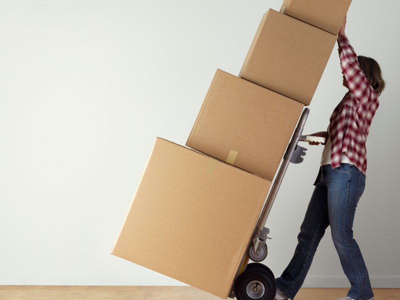 Person pushing a dolly loaded with moving boxes