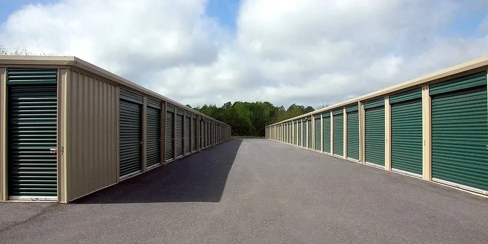 Best Mover Montreal: Row of storage units with green doors in an outdoor storage facility, ideal for storage during a move.