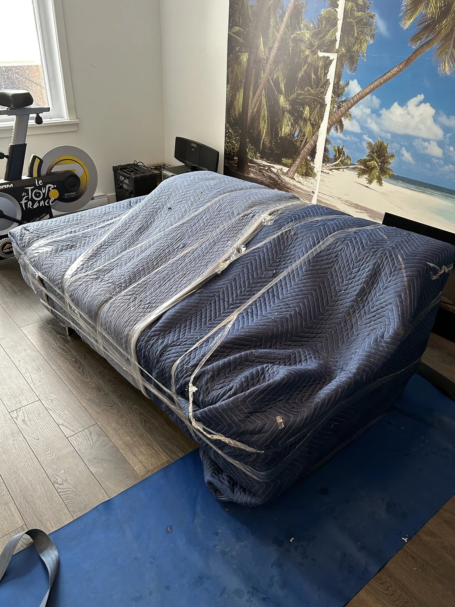 Matelas emballé avec des couvertures de protection bleues et sangles pour un déménagement sécurisé Matelas emballé avec des couvertures de protection bleues et sangles pour un déménagement sécurisé