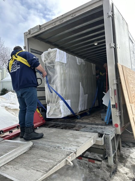 Best Mover Montreal: DMAX mover loading a large, protected piece of furniture into a truck using a lift gate during a winter move.