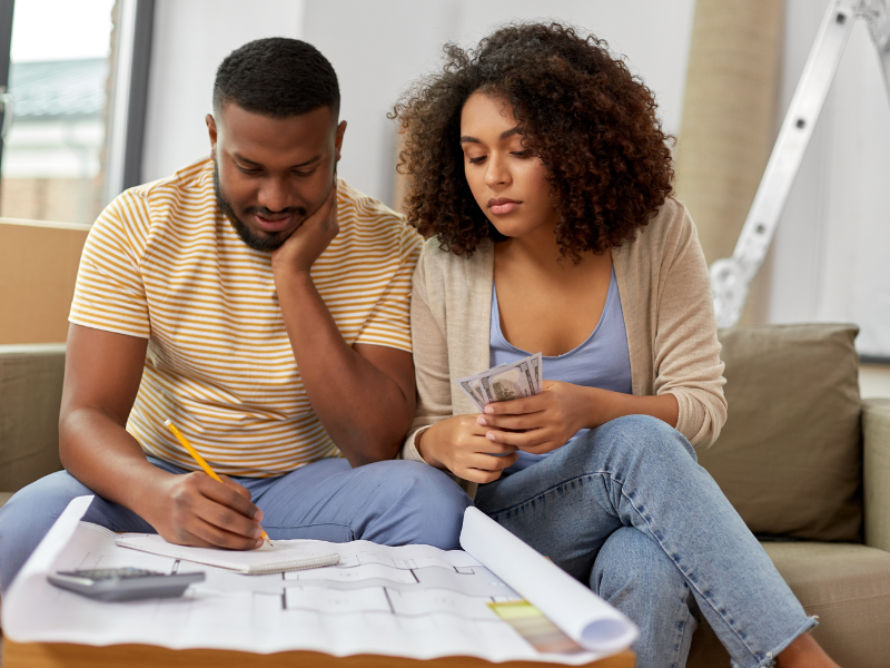 Budget-friendly move: Couple planning a move on a budget, reviewing plans and holding money.