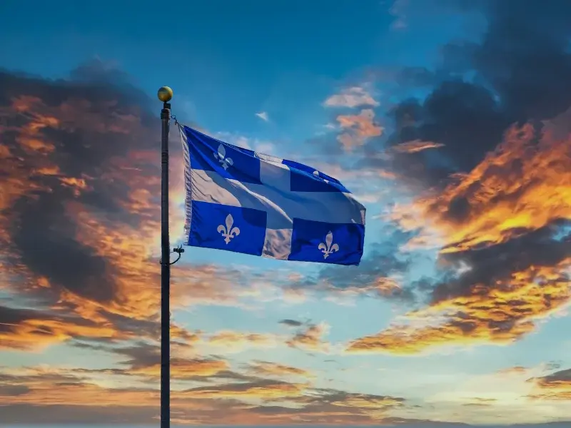 Déménagement clé en main : Drapeau du Québec flottant au coucher du soleil, symbole de déménagements DMAX partout dans la province Déménagement clé en main : Drapeau du Québec flottant au coucher du soleil, symbole de déménagements DMAX partout dans la province