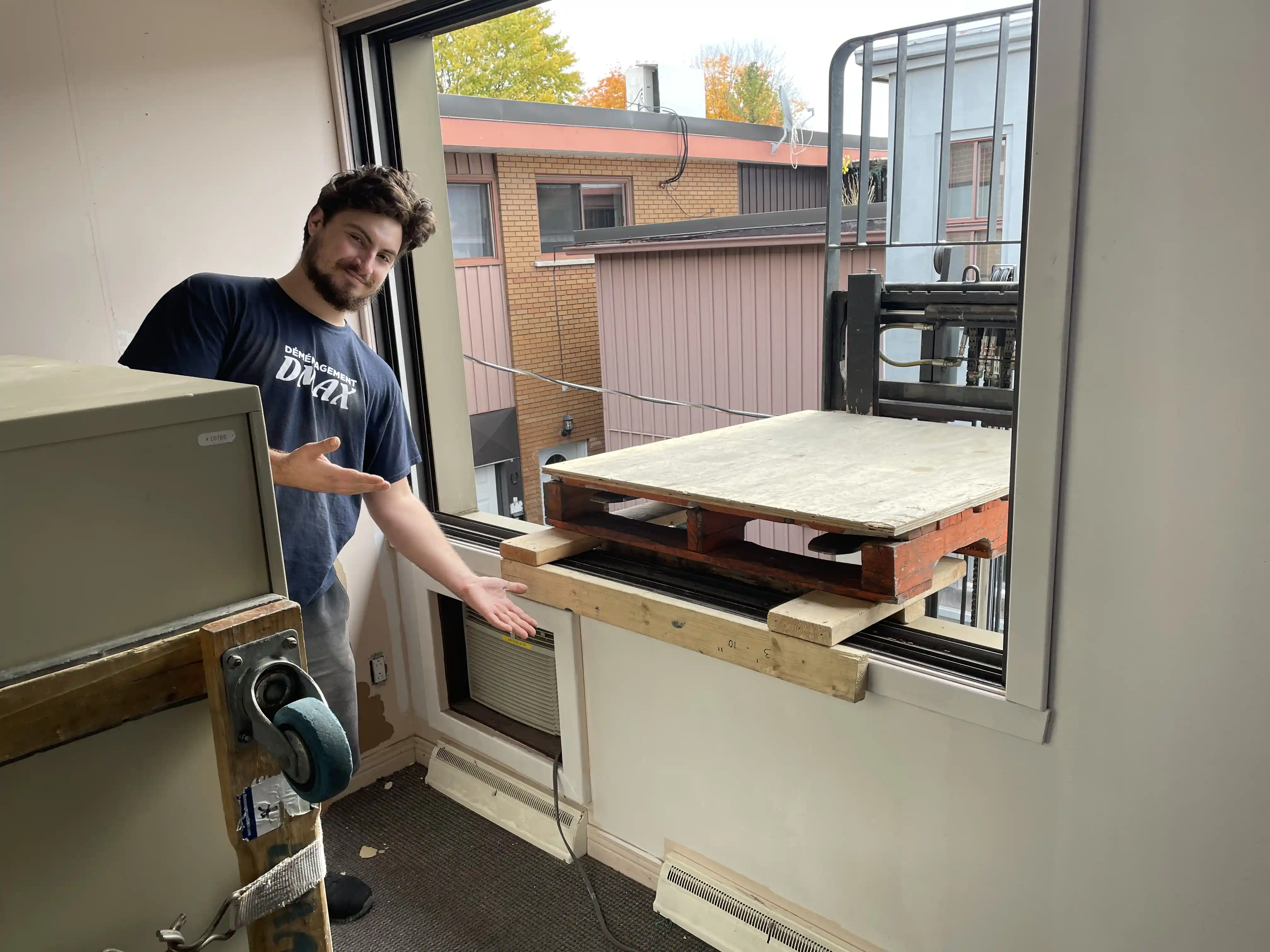 Mover beside a window where a forklift platform is set up to lift a safe out of the building