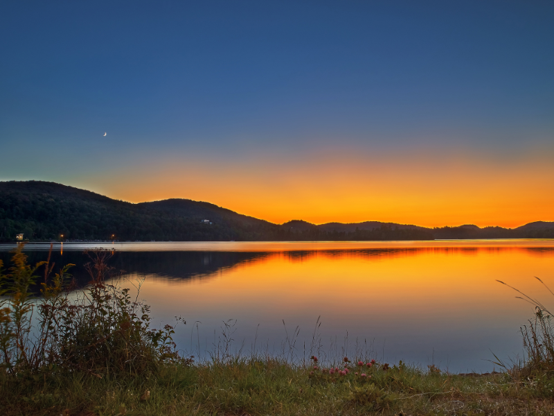 déménagement Laurentides : Coucher de soleil sur un lac avec un croissant de lune dans la région des Laurentides, Québec