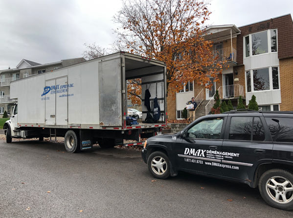 Déménagement local Laval - Camion et véhicule de DMAX Déménagement stationnés devant un immeuble résidentiel lors d’un déménagement