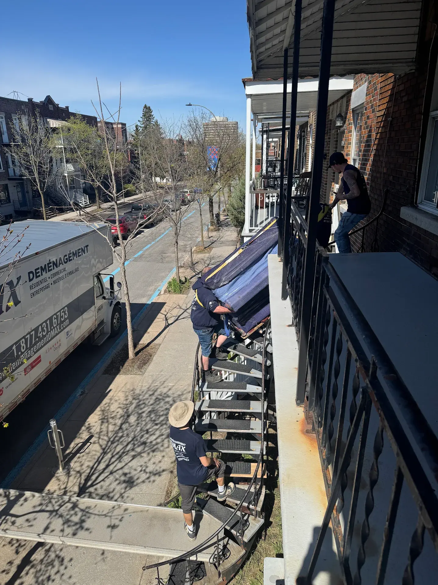 Déménageurs DMAX transportant un piano droit par un escalier extérieur lors d’un déménagement à Montréal