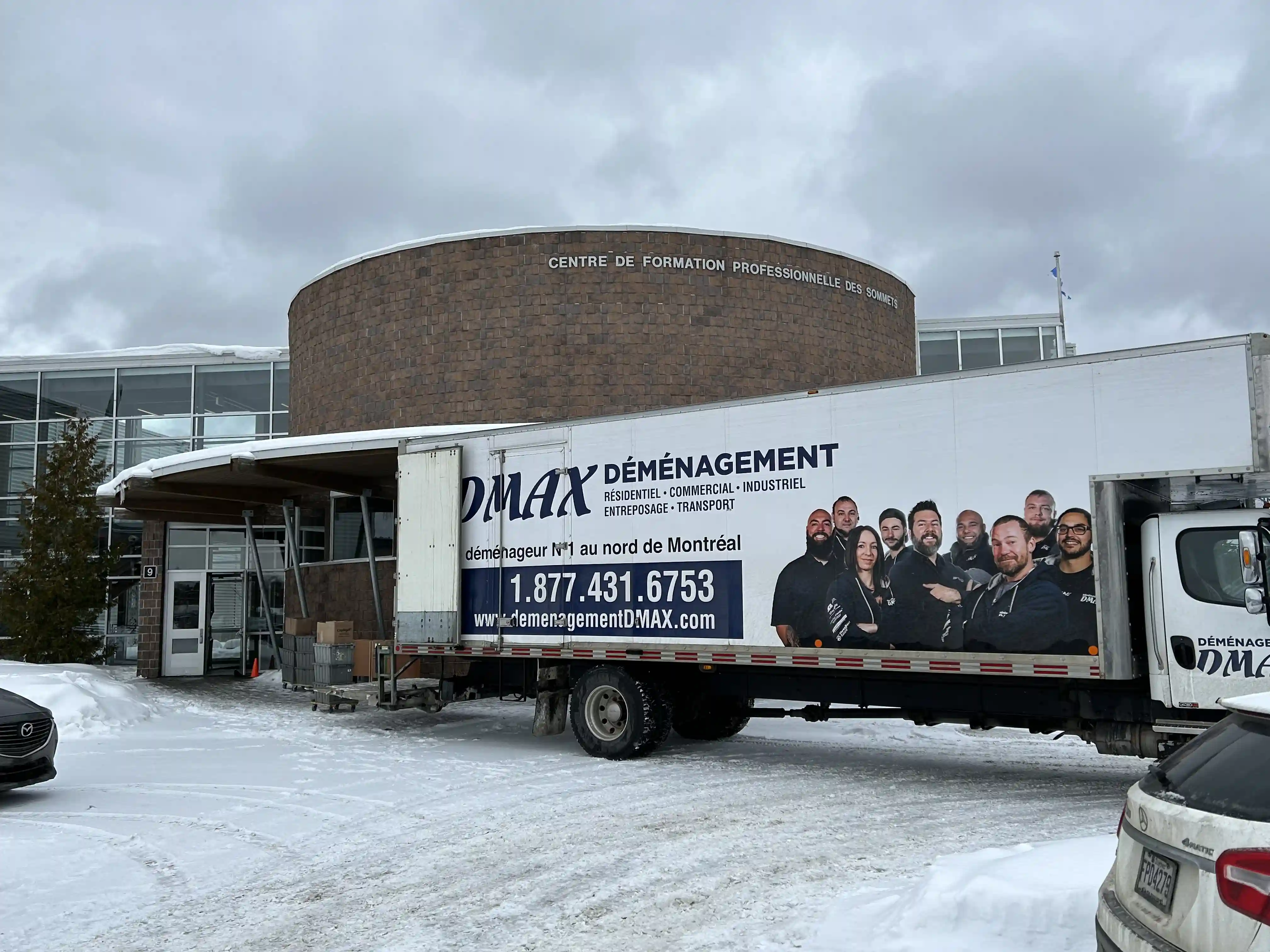 Camion de déménagement DMAX garé devant le Centre de Formation Professionnelle des Sommets en hiver, prêt pour un déménagement commercial.