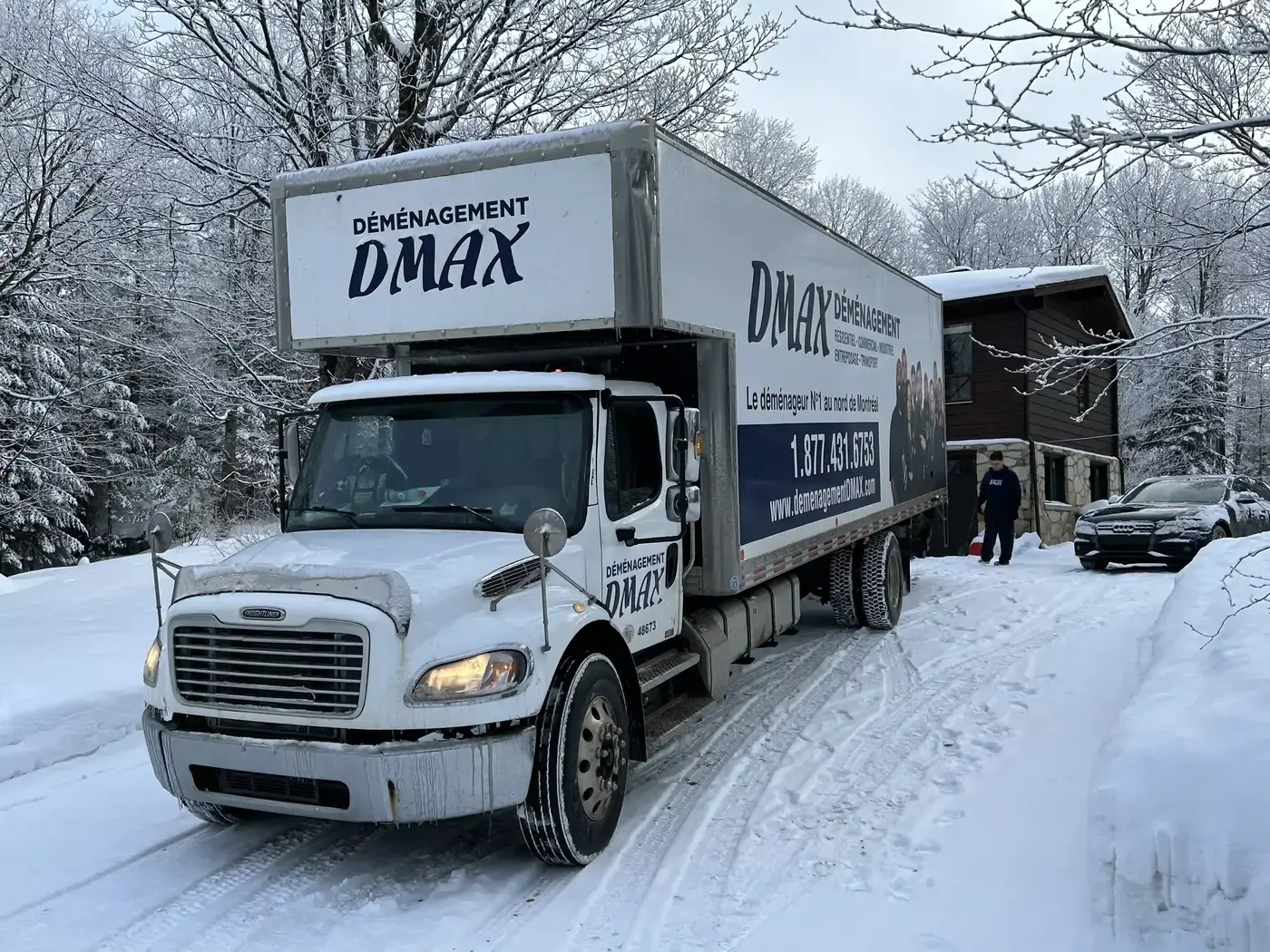 Moving Terrebonne: a Déménagement DMAX truck parked on a snowy street in front of a house, in winter