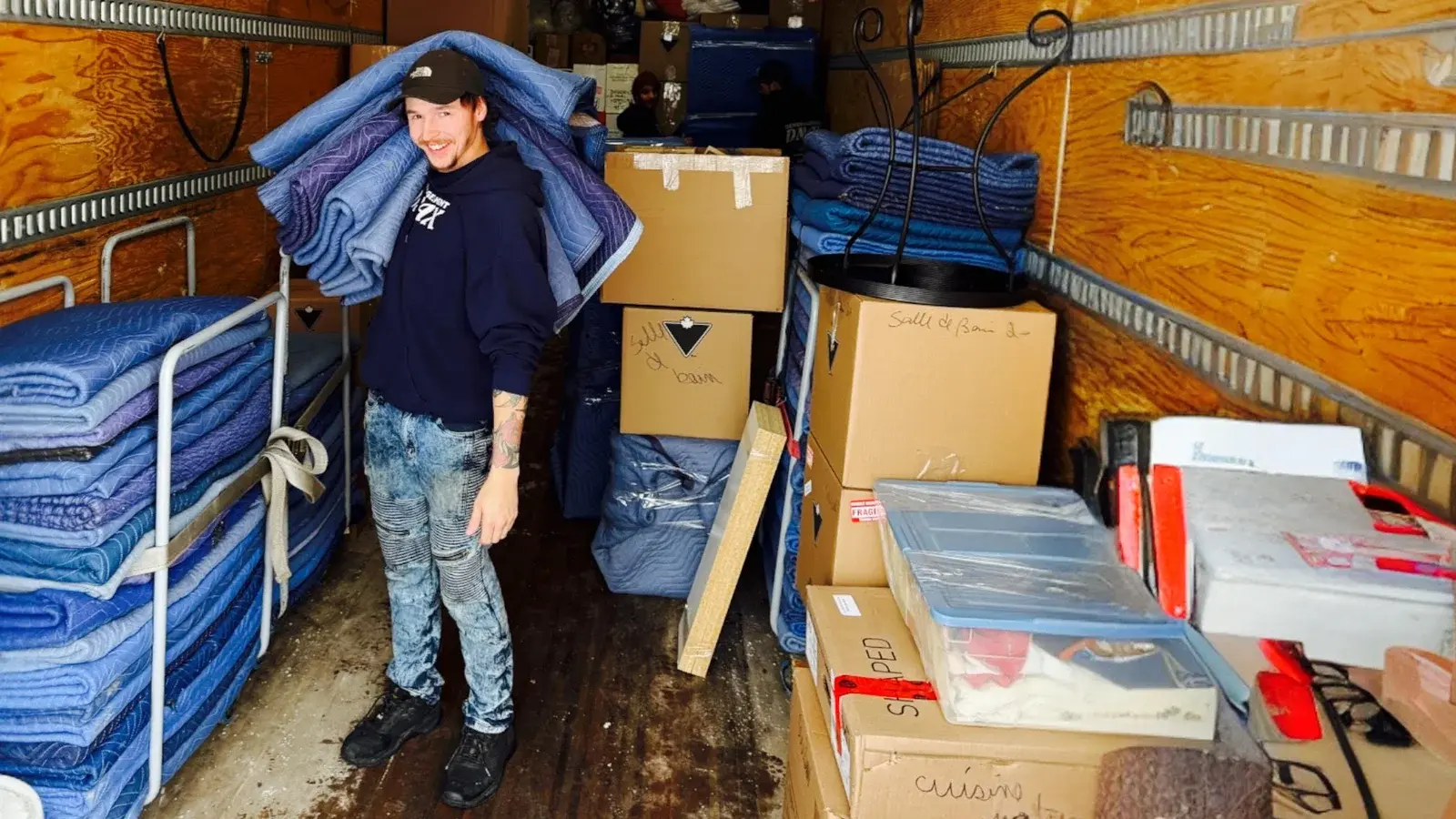 Moving Terrebonne: inside the truck, a mover carries a stack of padded moving blankets between the boxes