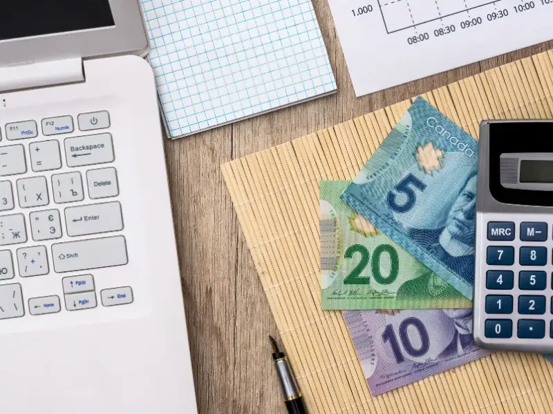 Argent canadien, calculatrice et ordinateur portable utilisés pour estimer les coûts d’un déménagement commercial
