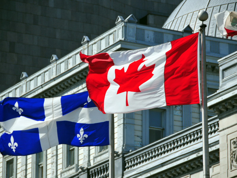Quebec and Canadian flags waving in front of a government building