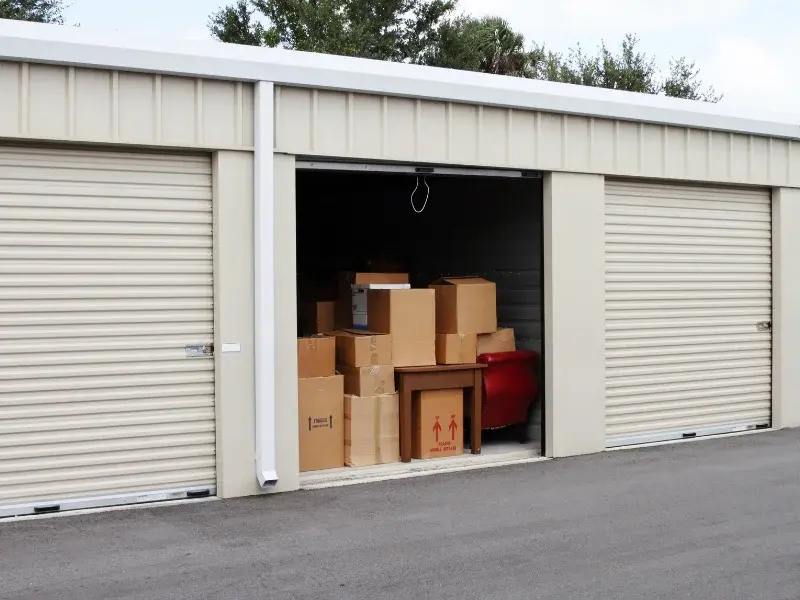 Espace d’entreposage avec cartons de déménagement et mobilier entreposés dans un box fermé Espace d’entreposage avec cartons de déménagement et mobilier entreposés dans un box fermé